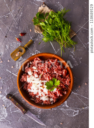 Homemade minced meat with ingredients for making in a bowl over dark slate, stone or concrete background. Homemade minced meat with ingredients for making in a bowl over dark slate, stone or concrete background. 118689529