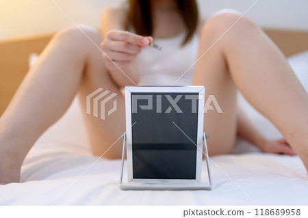A young woman taking care of her crotch area, a delicate VIO zone, tweezing hair with tweezers while looking in the mirror A young woman taking care of her crotch area, a delicate VIO zone, tweezing hair with tweezers while looking in the mirror 118689958