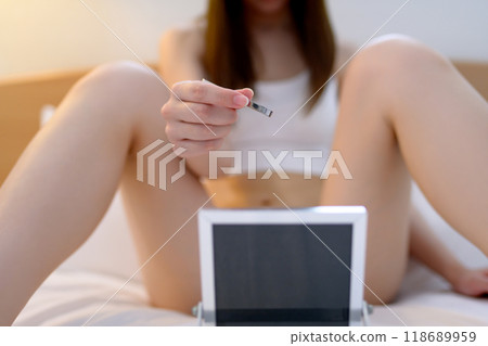 A young woman taking care of her crotch area, a delicate VIO zone, tweezing hair with tweezers while looking in the mirror A young woman taking care of her crotch area, a delicate VIO zone, tweezing hair with tweezers while looking in the mirror 118689959