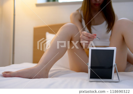 A young woman doing self-care for her VIO delicate zone groin area, tweezing hair with tweezers while looking in the mirror, negative dark A young woman doing self-care for her VIO delicate zone groin area, tweezing hair with tweezers while looking in the mirror, negative dark 118690322