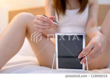 A young woman taking care of her VIO delicate zone crotch area herself, tweezing hair with tweezers while looking in the mirror, real color A young woman taking care of her VIO delicate zone crotch area herself, tweezing hair with tweezers while looking in the mirror, real color 118690328