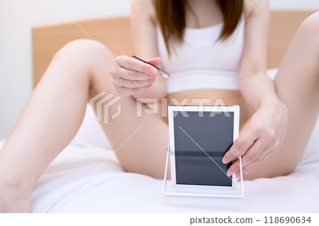 A young woman taking care of her VIO delicate zone crotch area herself, tweezing hair with tweezers while looking in the mirror, real color A young woman taking care of her VIO delicate zone crotch area herself, tweezing hair with tweezers while looking in the mirror, real color 118690634