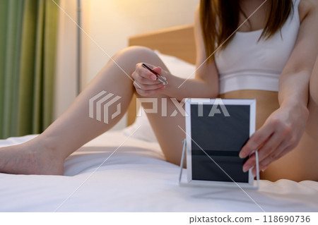 A young woman taking care of her crotch area, a delicate VIO zone, tweezing hair with tweezers while looking in the mirror A young woman taking care of her crotch area, a delicate VIO zone, tweezing hair with tweezers while looking in the mirror 118690736