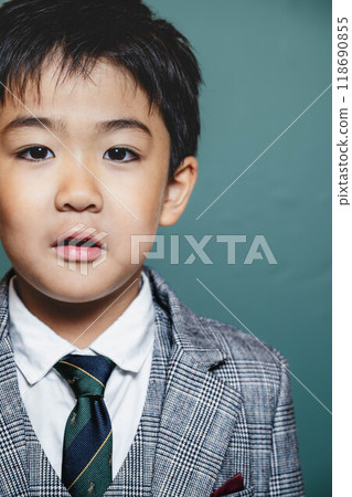 A child in a suit against a green screen 118690855