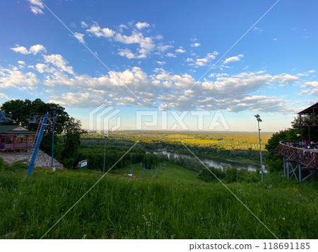 Scenic view of lush landscape with river and vast sky and the ski lift not work in summer. Panorama of nature captured from hilltop during serene summer day. Scenic view of lush landscape with river and vast sky and the ski lift not work in summer. Panorama of nature captured from hilltop during serene summer day. 118691185