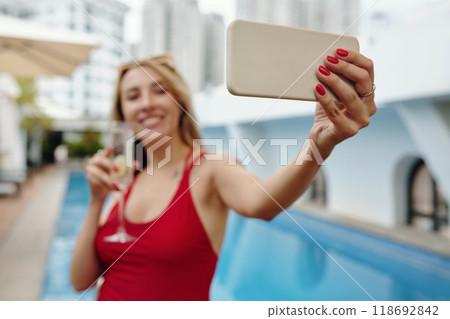 Taking Selfie by Swimming Pool Holding Cocktail Glass Taking Selfie by Swimming Pool Holding Cocktail Glass 118692842