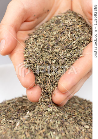 Seasoning dried basil in human hands, handful of chopped basil close-up 118692869
