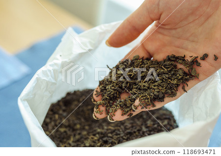 Woman holding paper bag with dry green tea leaves, close up 118693471
