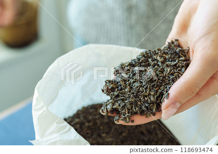 Woman holding paper bag with dry green tea leaves, close up Woman holding paper bag with dry green tea leaves, close up 118693474