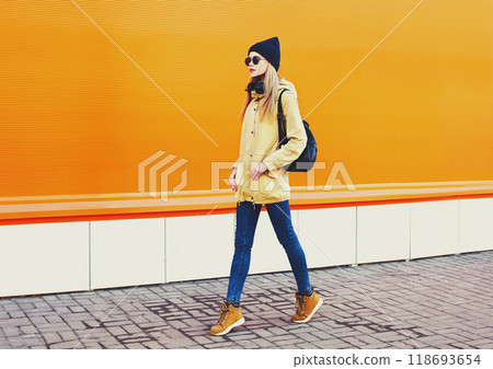 Fashion pretty blonde woman walking in city on a orange colorful background Fashion pretty blonde woman walking in city on a orange colorful background 118693654