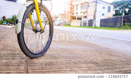 Wheel of a bicycle is flat parking on concrete sidewalk beside a road, need to be repaired, the moment of stillness and an unexpected pause in a journey. 118693757