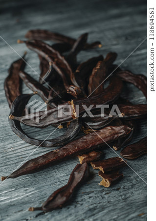 ripe carob pods on a wooden table 118694561