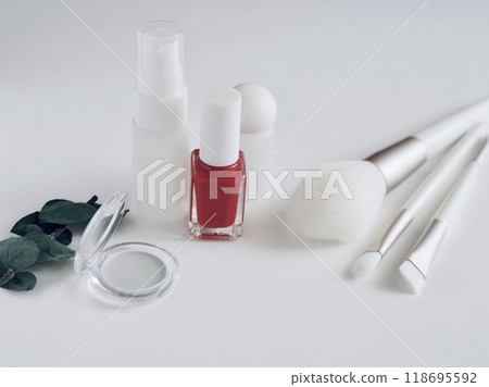 White cosmetic bottle and brush with red nail polish and plant leaves 118695592