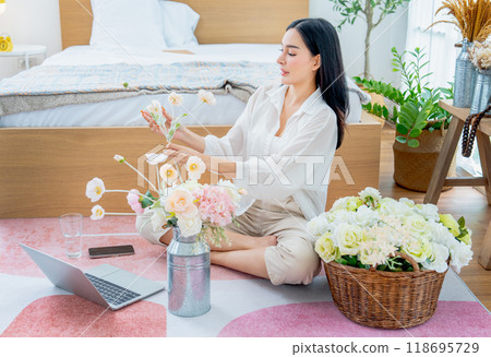 Beautiful Asian woman happy to do flower arrangement in bedroom of her house with relax time. 118695729