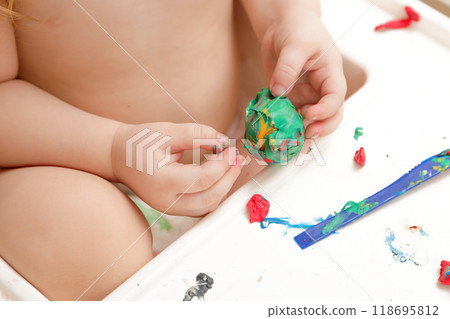 Baby hands holding and kneading red modeling clay 118695812
