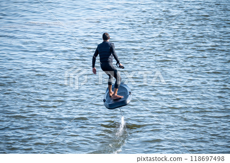 Silhouetted man on a hydrofoil surfboard 118697498