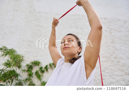 Woman practicing resistance band exercise outdoors for fitness and strength training Woman practicing resistance band exercise outdoors for fitness and strength training 118697516