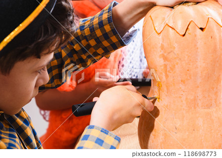 Close-up shot of a boy carving Halloween pumpkin with special saw knife 118698773
