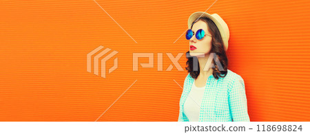 Portrait of young woman wearing summer straw round hat on orange background, blank copy space 118698824