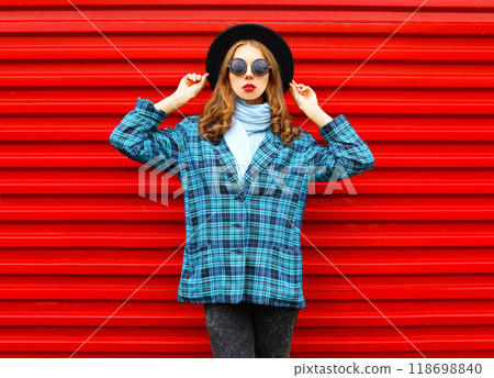 Fashion pretty woman wearing a black hat coat jacket over colorful red background Fashion pretty woman wearing a black hat coat jacket over colorful red background 118698840