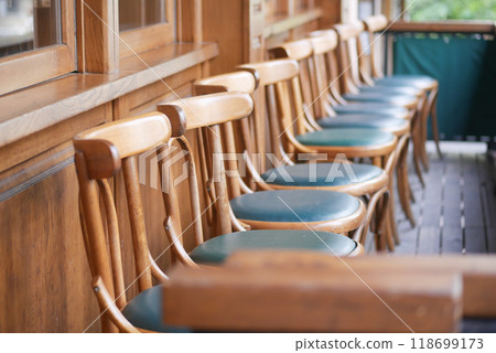 A row of beautifully crafted wooden chairs adorned with green cushions in a cozy, inviting setting A row of beautifully crafted wooden chairs adorned with green cushions in a cozy, inviting setting 118699173