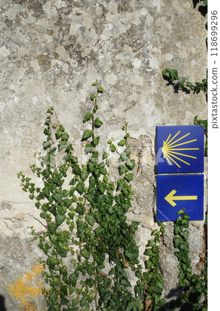 Signpost of the Saint James Way displaying the traditional yellow arrow and scallop 118699296
