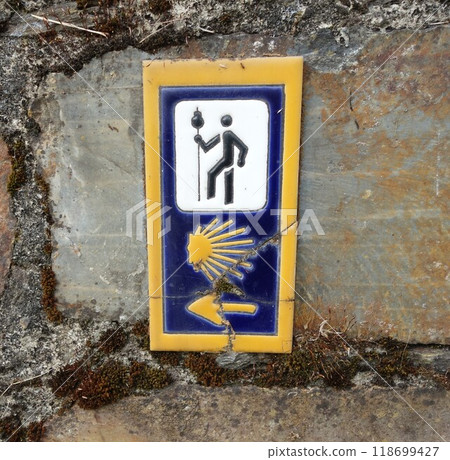 Signpost of the Saint James Way displaying the traditional yellow arrow and scallop Signpost of the Saint James Way displaying the traditional yellow arrow and scallop 118699427