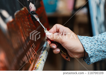 Artist applying black paint to canvas in brightly lit studio during daytime Artist applying black paint to canvas in brightly lit studio during daytime 118700109