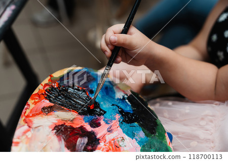 A child painting with vibrant colors on a palette during art class 118700113