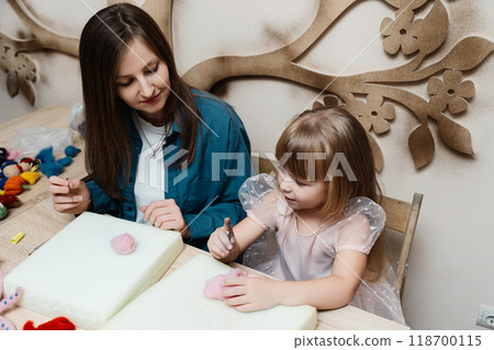 Mother and daughter crafting together at home in a cozy workshop 118700115