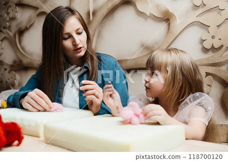 A mother and daughter enjoy crafting together in a cozy workshop setting 118700120
