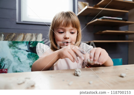 Girl engaged in creative play with modeling clay indoors 118700153