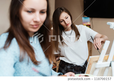 Two artists enjoying a creative painting session in a cozy studio space 118700157