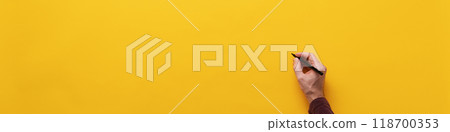 Male hand about to write on blank yellow background Male hand about to write on blank yellow background 118700353