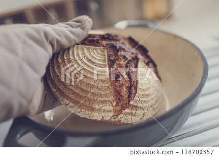 Taking hot bread out of clay pot 118700357