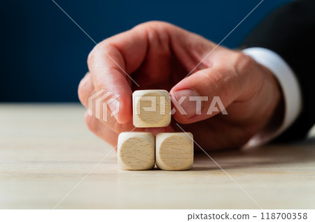 Businessman placing three blank wooden dices in a pyramid shape Businessman placing three blank wooden dices in a pyramid shape 118700358