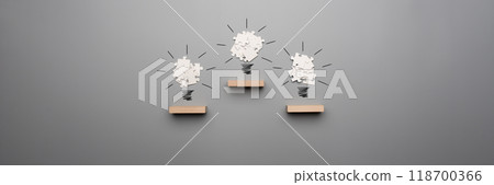 Wide panorama view of three light bulb formed by white puzzle pieces placed on wooden pegs Wide panorama view of three light bulb formed by white puzzle pieces placed on wooden pegs 118700366
