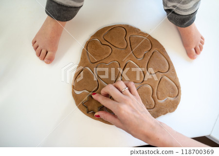 Top view of a mother pressing heart shape cookie cutter in rolled dough Top view of a mother pressing heart shape cookie cutter in rolled dough 118700369