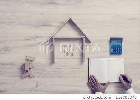 Businessman calculating the costs of a residential house while writing notes 118700376