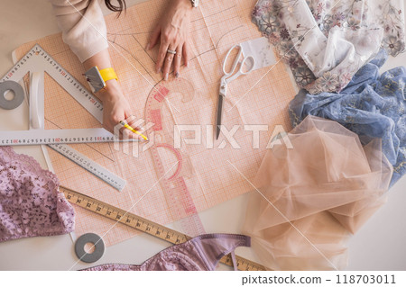 A woman seamstress designs and draws a pattern for underwear on graph paper.  118703011