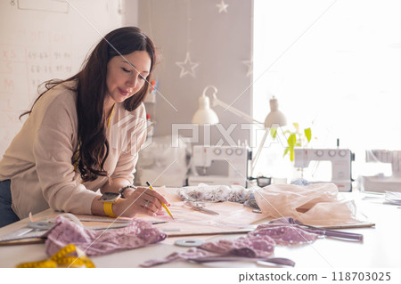 A woman seamstress designs and draws a pattern for underwear on graph paper.  118703025