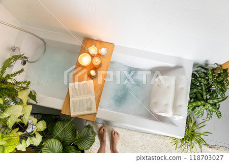 A woman stands in front of a bathtub filled with white foam. The concept of relaxation, self-love 118703027
