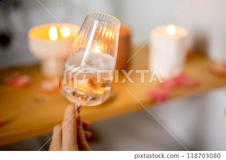 A young beautiful girl drinks wine while lying in a bath with foam and petals. Candles and plants. A young beautiful girl drinks wine while lying in a bath with foam and petals. Candles and plants. 118703080