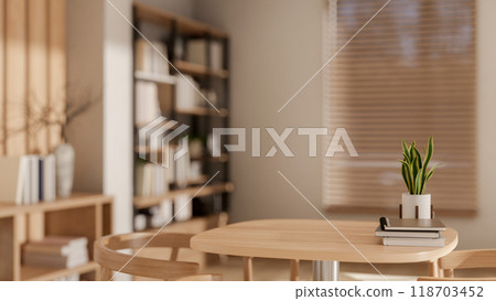 A wooden table in a cozy, contemporary home or cafe, featuring books and a decor plant on the table. 118703452