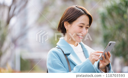 Woman using a smartphone (winter clothes, jacket, coat) Woman using a smartphone (winter clothes, jacket, coat) 118703593