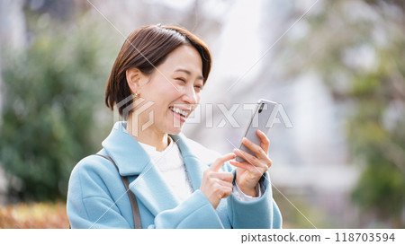 Woman using a smartphone (winter clothes, jacket, coat) Woman using a smartphone (winter clothes, jacket, coat) 118703594