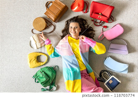 A young beautiful girl lies on the floor in the dressing room, surrounded in a circle by fashionable A young beautiful girl lies on the floor in the dressing room, surrounded in a circle by fashionable 118703774