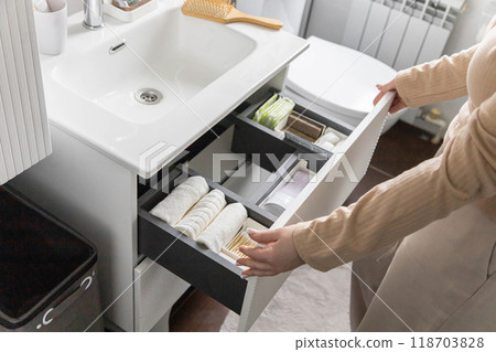 Top view of woman hands neatly organizing bathroom amenities and toiletries in drawer in bathroom. Top view of woman hands neatly organizing bathroom amenities and toiletries in drawer in bathroom. 118703828