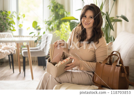 A young beautiful woman is collecting her women's bag. He puts away his diary, glasses, keys, phone A young beautiful woman is collecting her women's bag. He puts away his diary, glasses, keys, phone 118703853