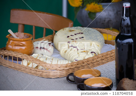Assorted sliced cheeses with honey and cups on a table 118704058